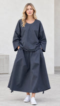 Front view of model wearing charcoal grey two-piece long sleeve top and maxi skirt set