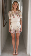 Front view of woman wearing off-white floral top and matching shorts set