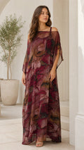 Front view of woman wearing burgundy abstract print cold-shoulder sheer overlay maxi dress