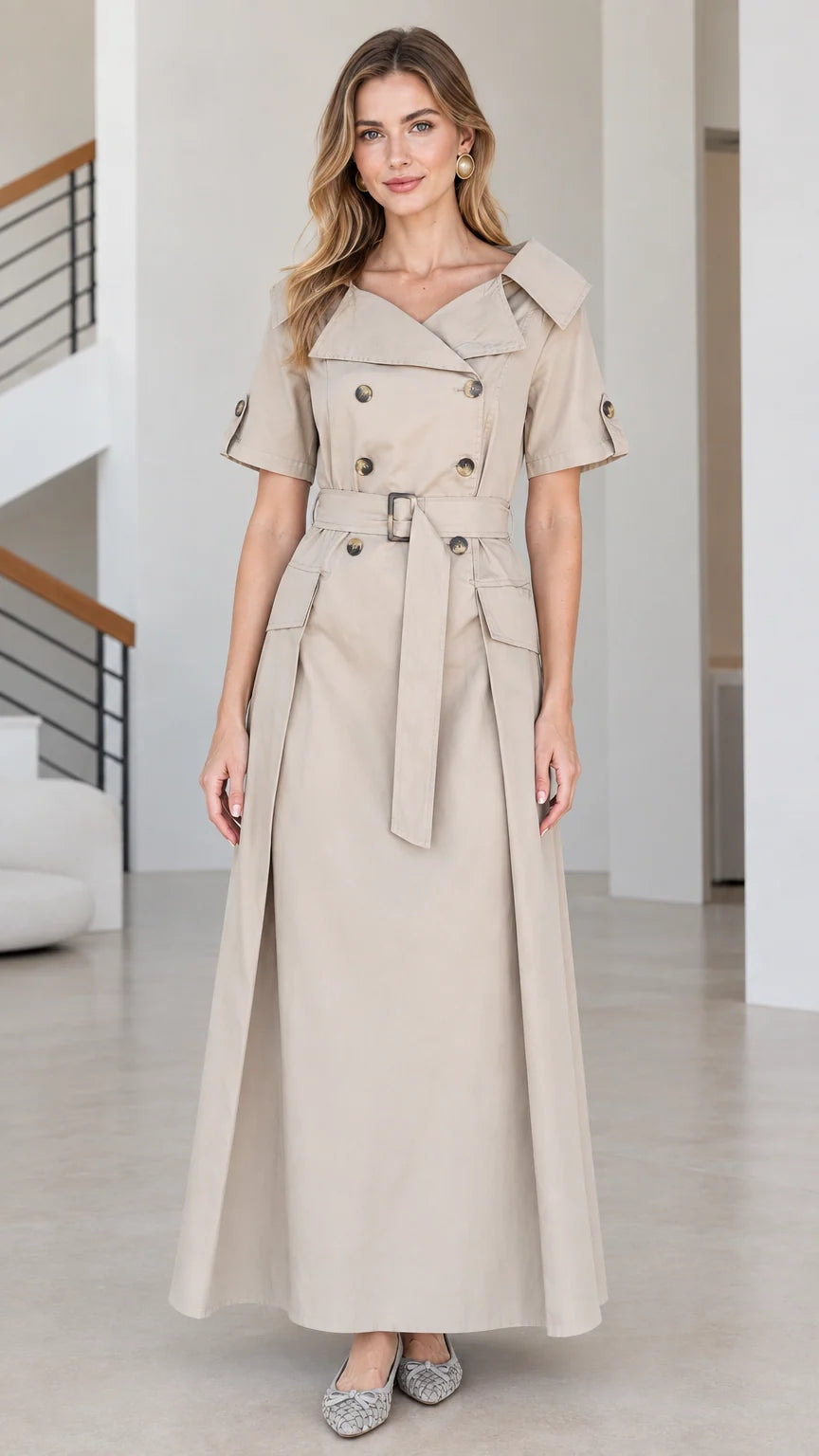 Front view of woman wearing beige double-breasted short-sleeve trench maxi dress with belt