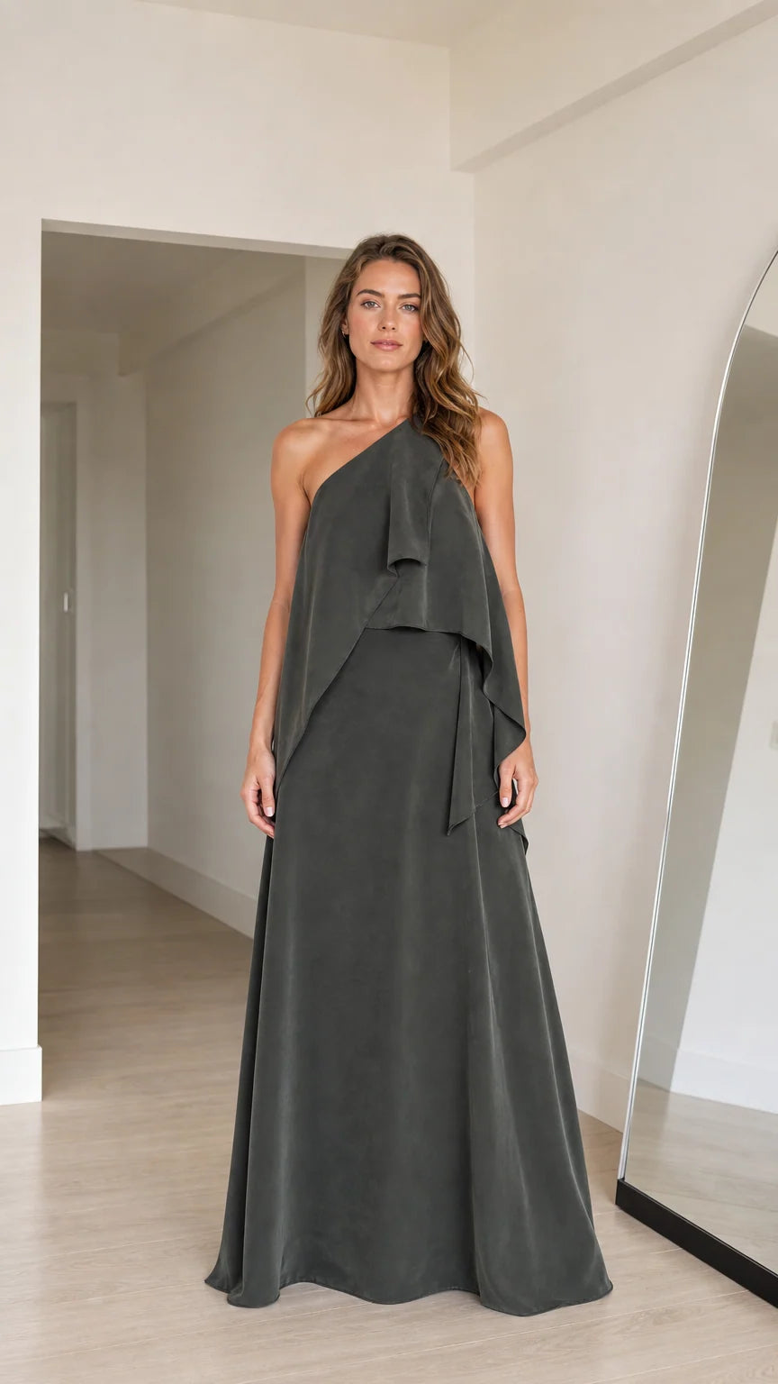 Front view of model wearing charcoal grey one-shoulder tiered draped maxi dress