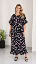 Full front view of women's black floral print tie-neck top and ruffle maxi skirt two-piece set