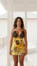 Front view of woman wearing yellow tie-dye mini slip dress with black lace trim