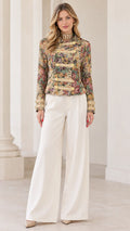 Full front view of model wearing Multi Floral tapestry military jacket with white wide-leg trousers