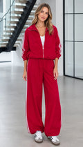 Front view of woman wearing red 2-piece tracksuit set with white side stripes