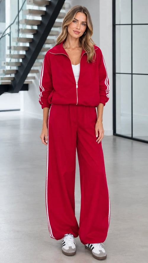 Front view of woman wearing red 2-piece tracksuit set with white side stripes