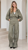 Front full view of woman wearing an olive green utility cargo jumpsuit with balloon sleeves and strapped hems