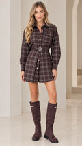 Front full-length view of model wearing brown plaid long sleeve belted shirt dress with knee-high boots