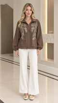 Front full-length view of woman wearing brown sequin embroidered zip jacket and white wide-leg trousers