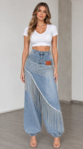 Front view of woman wearing light blue rhinestone fringe denim balloon pants with white crop top