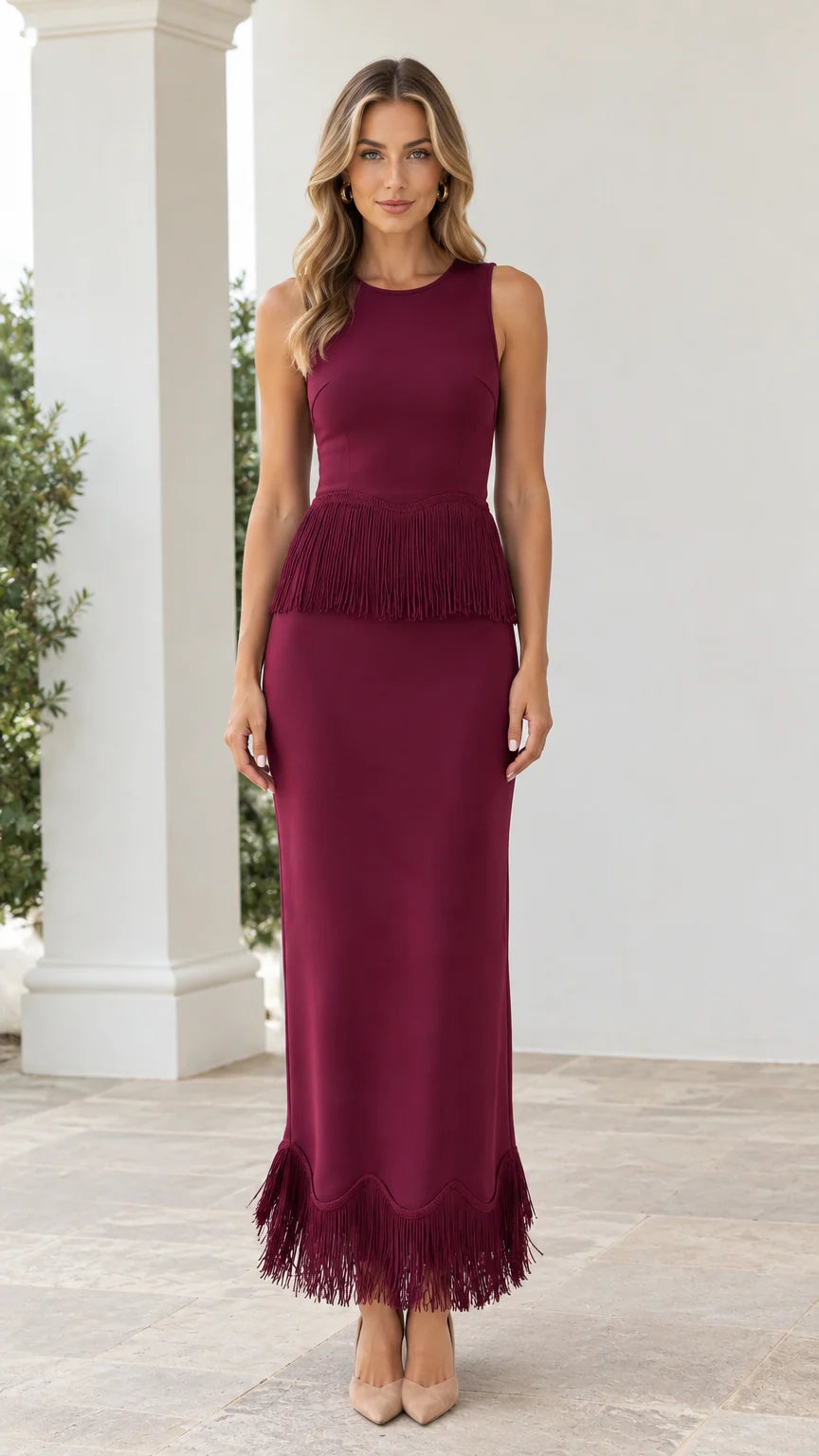 Front view of woman wearing burgundy sleeveless maxi dress with waist and hem fringe