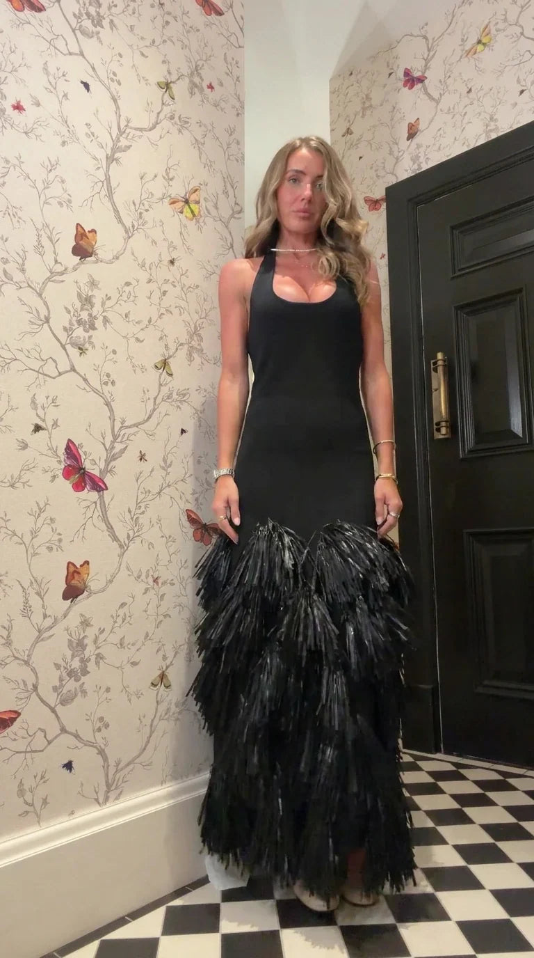Front view of woman wearing black halter neck maxi dress with tiered fringe skirt