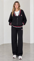 Full front view of model wearing black varsity striped zip jacket and wide leg sweatpants set