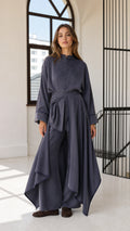 Front full view of woman wearing slate blue asymmetric draped tunic and matching wide-leg trousers set