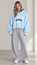 Front view of woman wearing Light Blue Chicago graphic cropped hoodie with gray sweatpants
