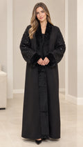 Front full-length view of model wearing black open-front abaya coat with faux fur collar and sequined sleeves