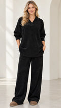 Front full view of woman wearing black ribbed knit V-neck tunic top and matching wide leg pants set