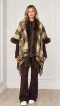Woman wearing olive khaki plaid poncho with faux fur collar and fringe hem - front view