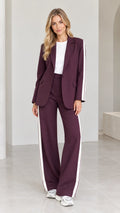Full front view of model wearing burgundy 2-piece blazer and wide-leg pants suit with white side stripes