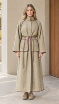 Front full-length view of woman wearing sage green herringbone piped maxi coat