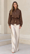 Front view of model wearing brown drawstring utility jacket with lace hem and satin maxi skirt