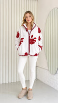 Model wearing white fleece jacket with red floral pattern and contrast trim front view