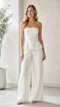 Model wearing white strapless lace peplum wide leg jumpsuit front view