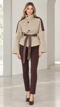 Front view of model wearing beige high-neck belted short trench jacket with brown trousers