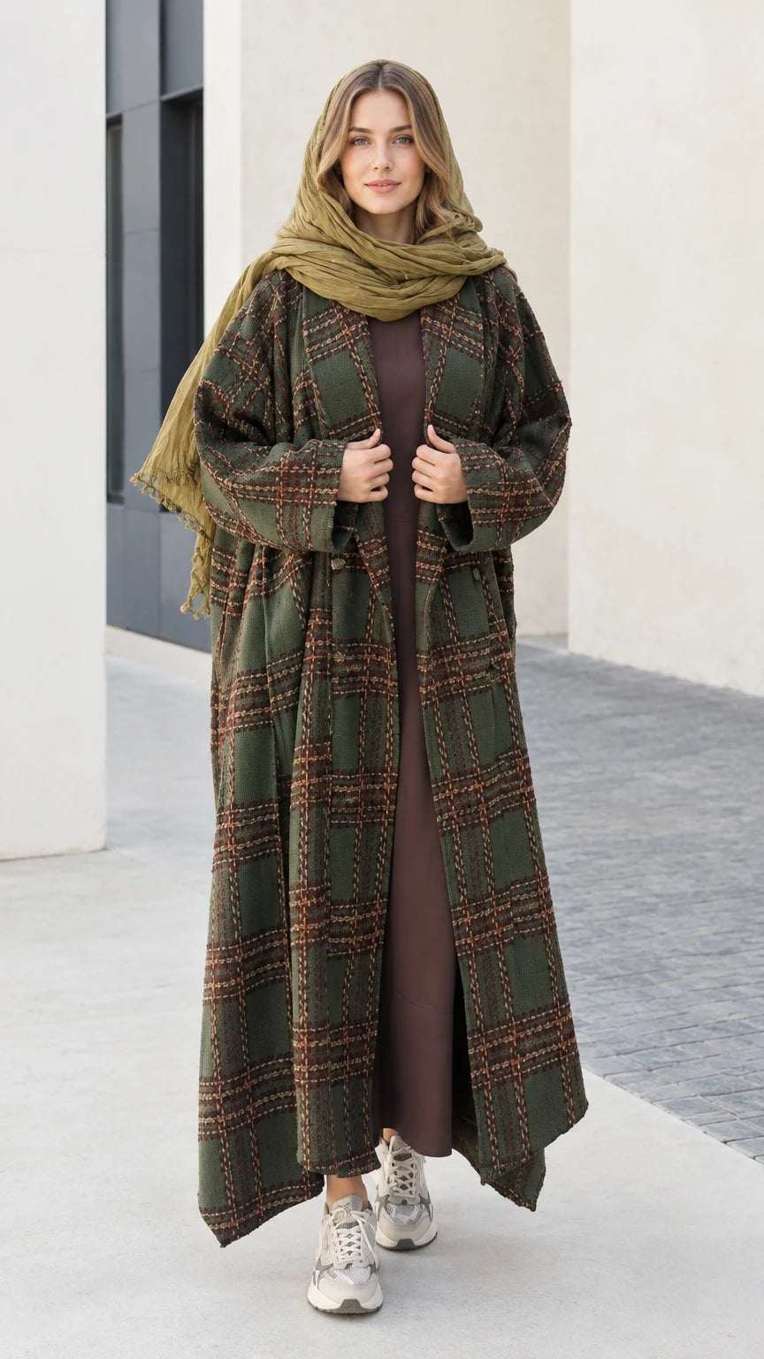 Front view of woman wearing olive green plaid maxi duster coat with matching green scarf