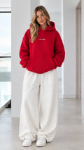 Women's oversized red pullover hoodie paired with white wide-leg sweatpants - front view