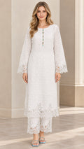 Front view of woman wearing white eyelet embroidered long tunic and matching lace-trimmed pants set
