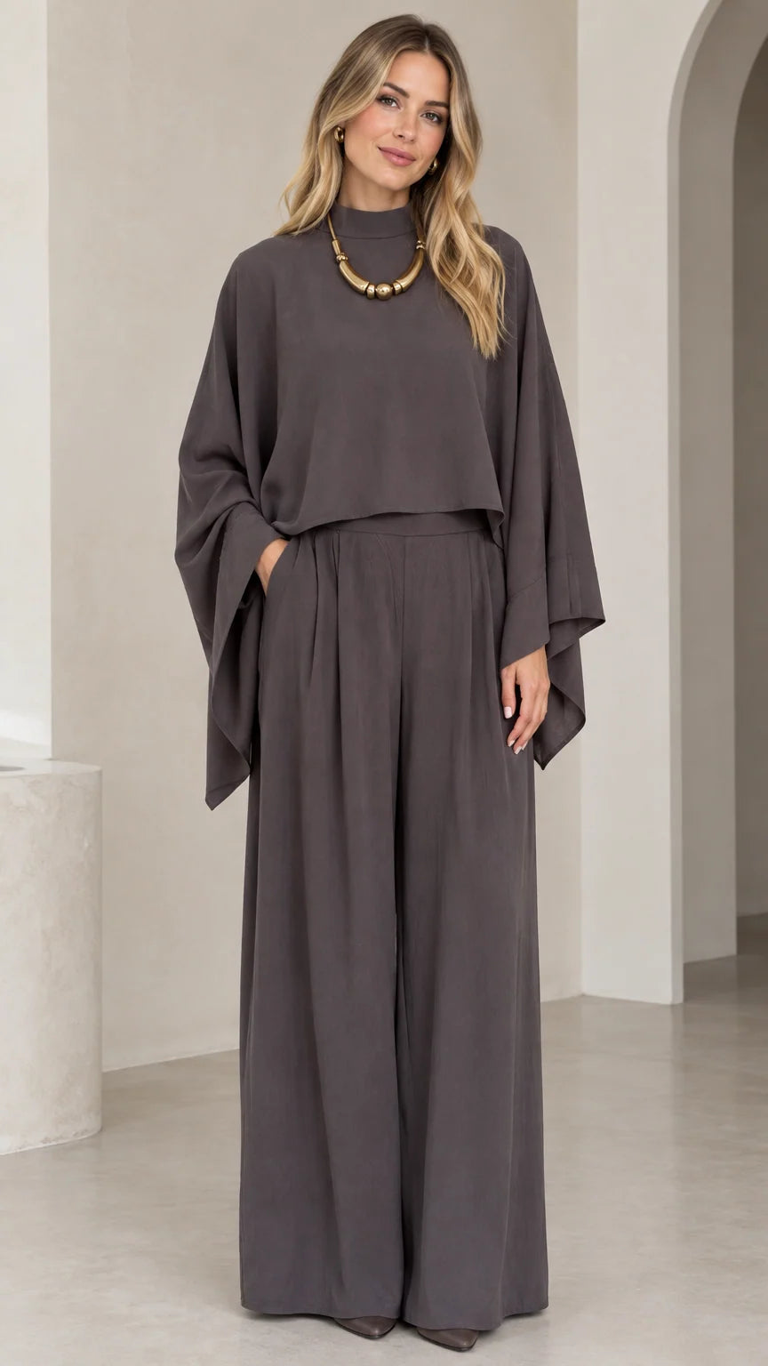 Front full-length view of woman wearing charcoal grey mock neck cape top and pleated wide leg pants set