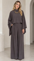 Front full-length view of woman wearing charcoal grey mock neck cape top and pleated wide leg pants set