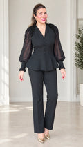 Front view of woman wearing black 2-piece peplum pant suit with beaded shoulders and sheer sleeves