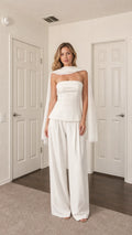 Front view of model wearing white strapless top, wide-leg pants, and scarf