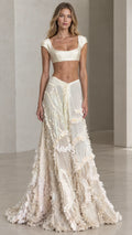 Front view of model wearing ivory two-piece satin crop top and ruffled maxi skirt