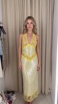 Model wearing Pale Yellow halter sequin maxi dress with yellow floral lace trim, front view