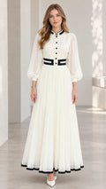 Front full-length view of woman wearing white pleated lantern sleeve maxi dress with black contrast trim