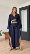 Model wearing indigo blue two-piece crop top and asymmetrical maxi skirt set, front view