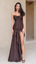Front full-length view of model in chocolate brown strapless draped maxi dress with front slit