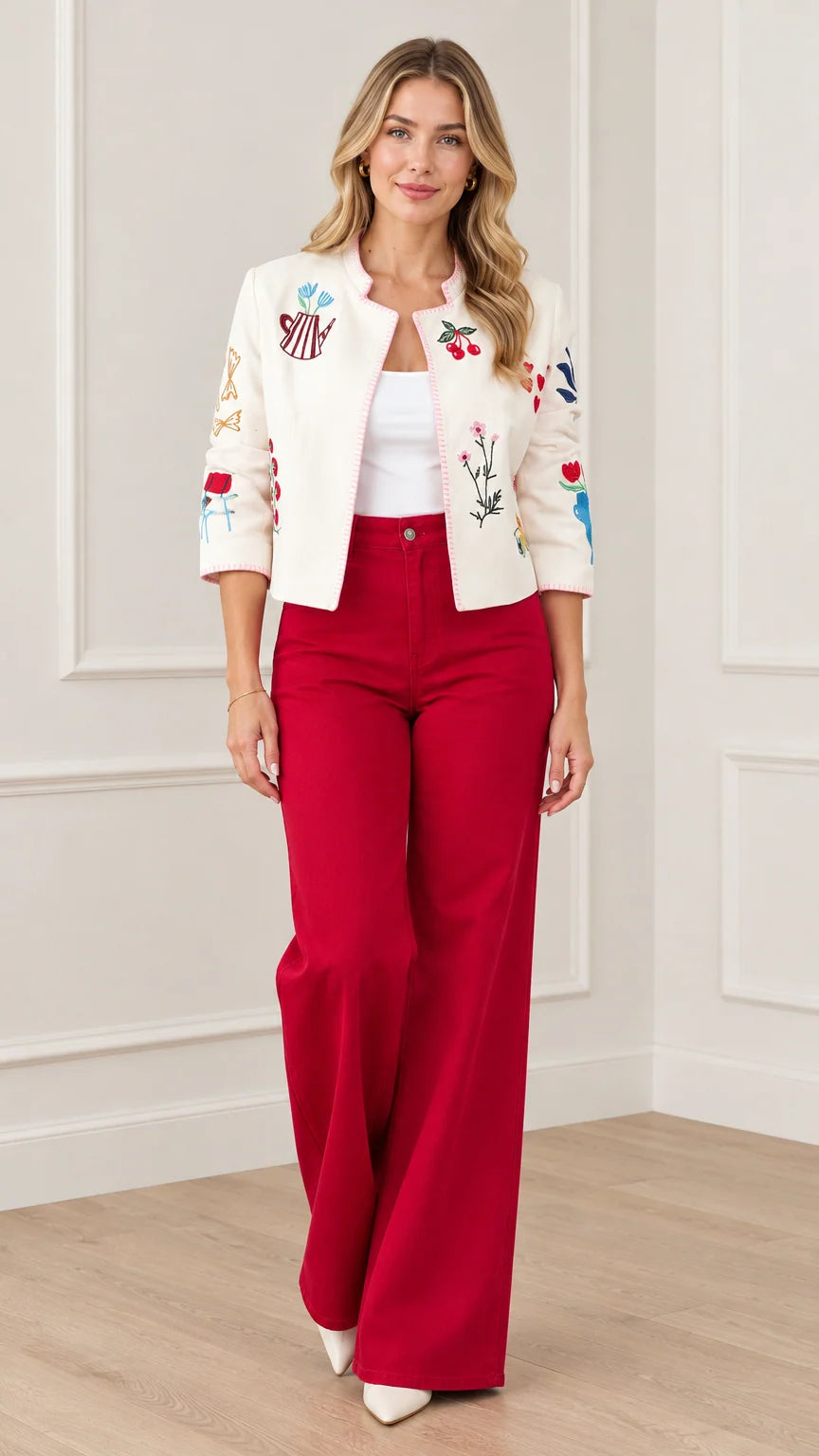 Front view of model wearing cream embroidered cropped jacket with red wide-leg trousers