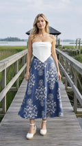 Front view of blue floral midi skirt paired with white top on wooden dock
