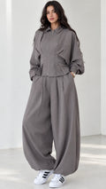 Model wearing grey zip-front top and balloon pants matching two-piece set front view