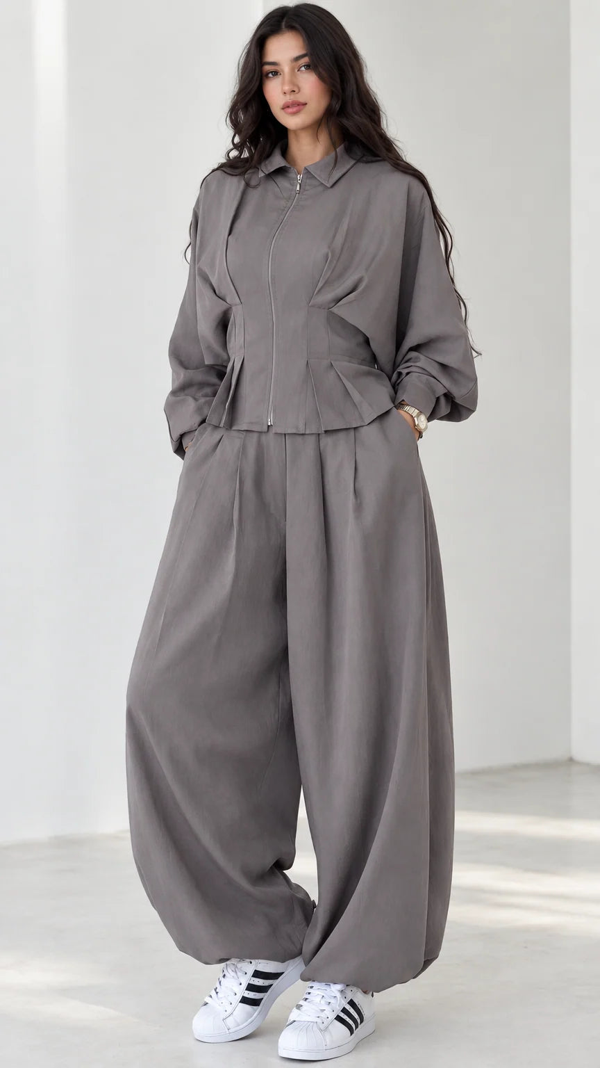 Model wearing grey zip-front top and balloon pants matching two-piece set front view