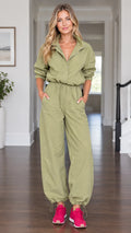 Front view of model wearing olive green utility parachute jumpsuit with drawstring waist