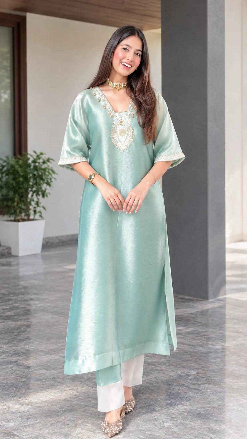 Front view of woman wearing sage green embroidered silk blend tunic kurta with white pants