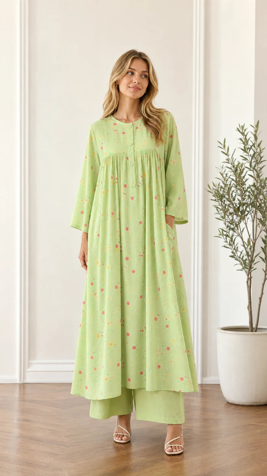 Front view of woman wearing light green floral pleated maxi dress with wide-leg pants