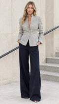 Front view of model wearing light grey stand collar tweed blazer with navy wide-leg trousers