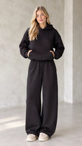 Front view of woman wearing black oversized hoodie and matching wide leg sweatpants