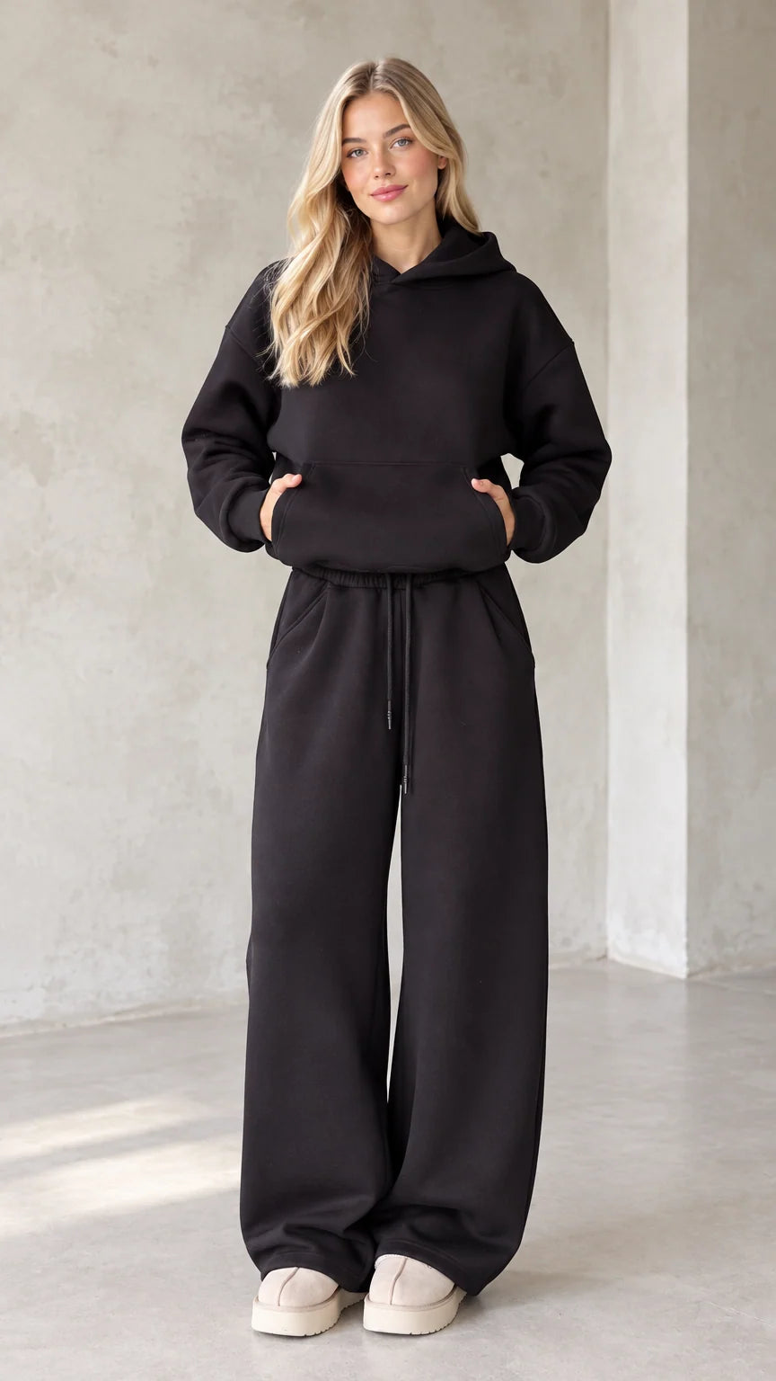 Front view of woman wearing black oversized hoodie and matching wide leg sweatpants
